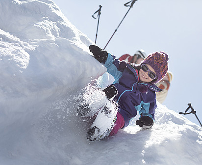 Kind rutscht einen Schneeberg runter im Skiurlaub im Familienhotel Sillian