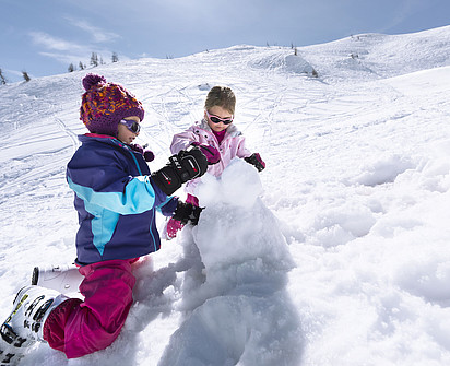 Kinder machen einen Schneemann im Aktivurlaub im Sporthotel Sillian in Osttirol