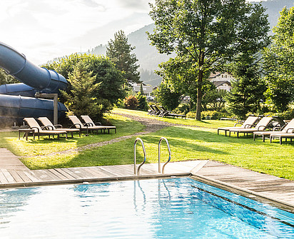 das Outdoor Pool mit einer Rutsche im Wellnesshotel Sillian in Osttirol