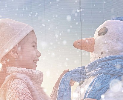 Mädchen mit einem Schneemann im Winterurlaub im Sporthotel Sillian in Osttirol